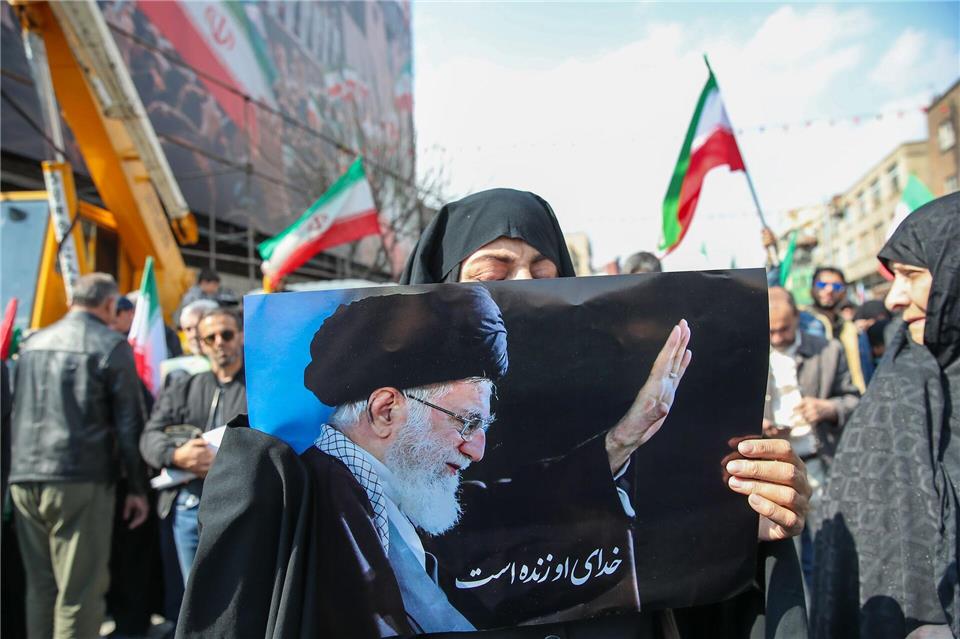 Eine Trauernde hält beim Begräbnis des von Israel getöteten Generalsekretärs des iranischen Sicherheitsrats, Ali Laridschani, ein Bild des ebenfalls getöteten Obersten Führers Ajatollah Ali Chamenei in die Höhe. Stringer/dpa