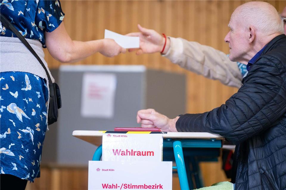Eine Wahlhelferin gibt einen Stimmzettel aus. Landesweit fällt die Wahlbeteiligung unterschiedlich aus. Benjamin Westhoff/dpa
