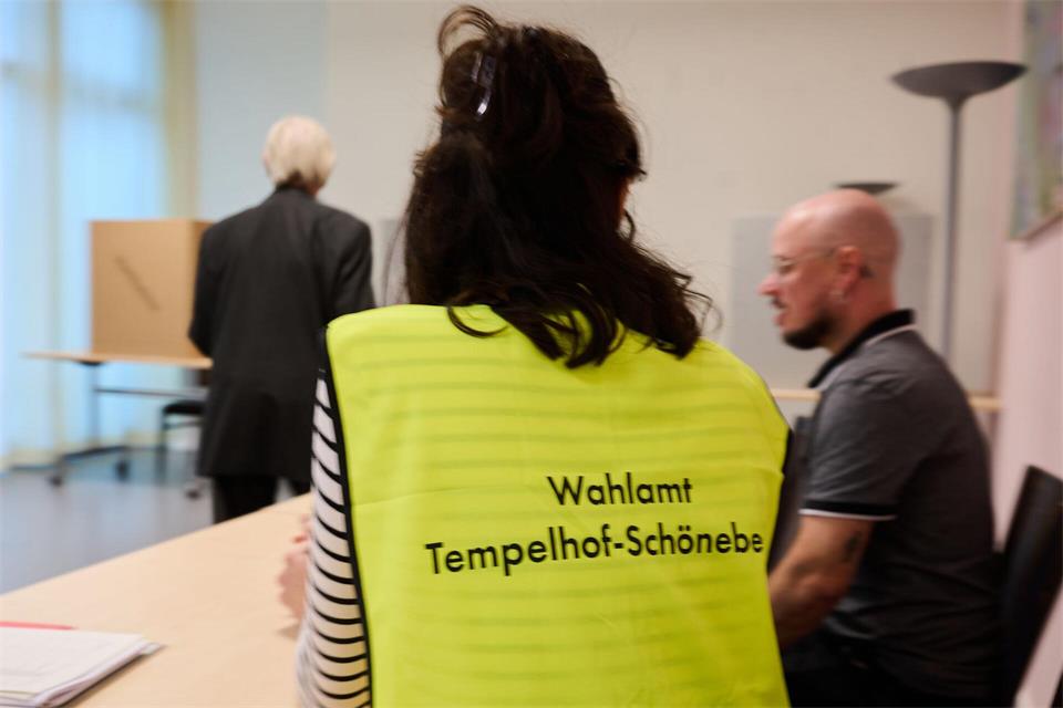 Eine Wahlhelferin trägt eine Weste mit der Aufschrift „Wahlamt Tempelhof-Schöneberg“.Annette Riedl/dpa