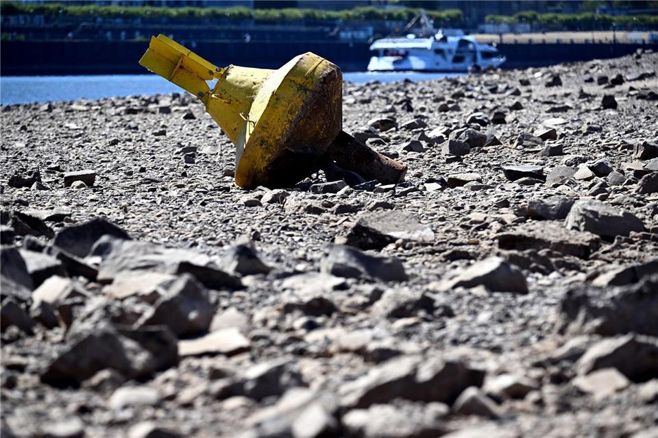 Eine gelbe Tonne liegt bei niedrigem Wasserstand des Rheins auf dem Trockenen. Federico Gambarini/dpa