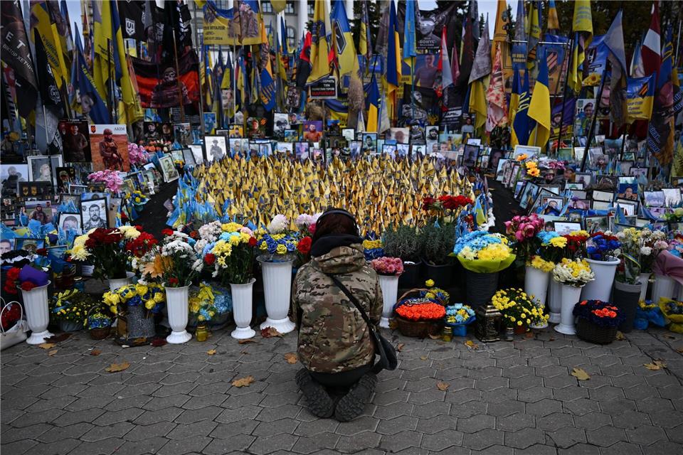 Eine junge Frau kniet am Unabhängigkeitsplatz Maidan in Kiew. Hier wird den Gefallenen des Krieges gedacht.Hendrik Schmidt/dpa