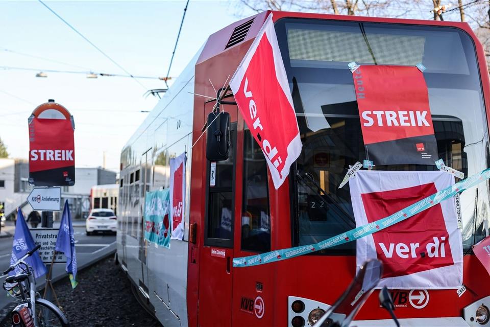 Eine mit Streik-Plakaten beklebte Straßenbahn der Kölner Verkehrs-Betriebe (KVB) steht vor dem Bahndepot.