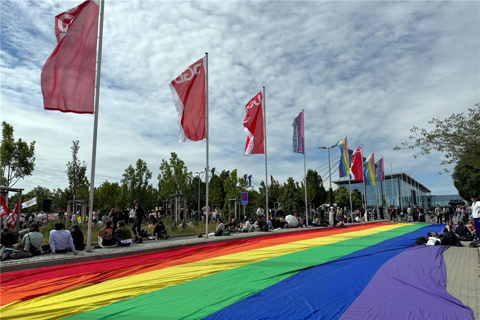 Eine übergroße Regenbogenfahne liegt ausgebreitet neben einer Kundgebung des DGB in ErfurtSarah Knorr/dpa