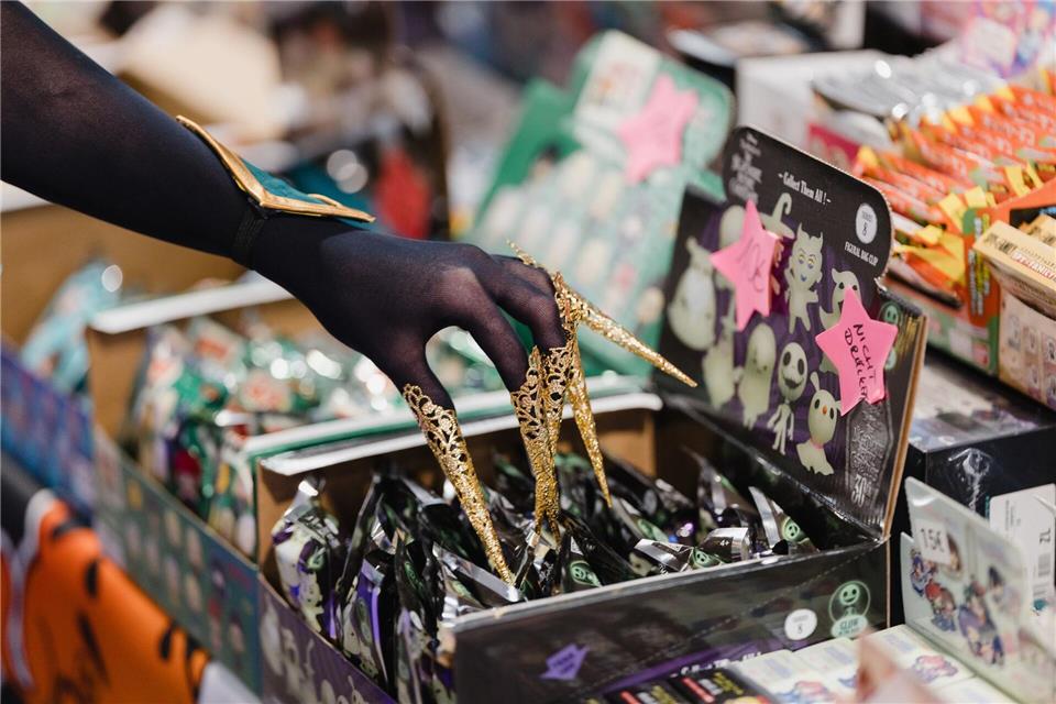 Eine verkleidete Messebesucherin berührt auf der Manga- und Comic-Messe „MAG-C“ ausgestellte Produkte. Michael Reichel/dpa