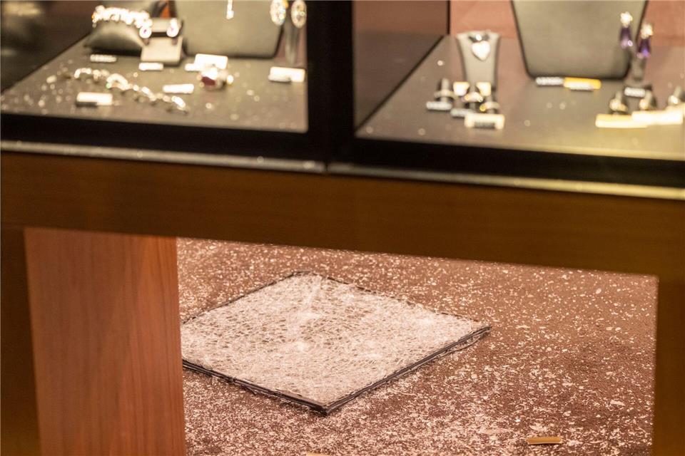 Eine zerbrochene Scheibe liegt nach dem Überfall in einem Juweliergeschäft in der Innenstadt auf dem Boden des Ladens.Peter Kneffel/dpa