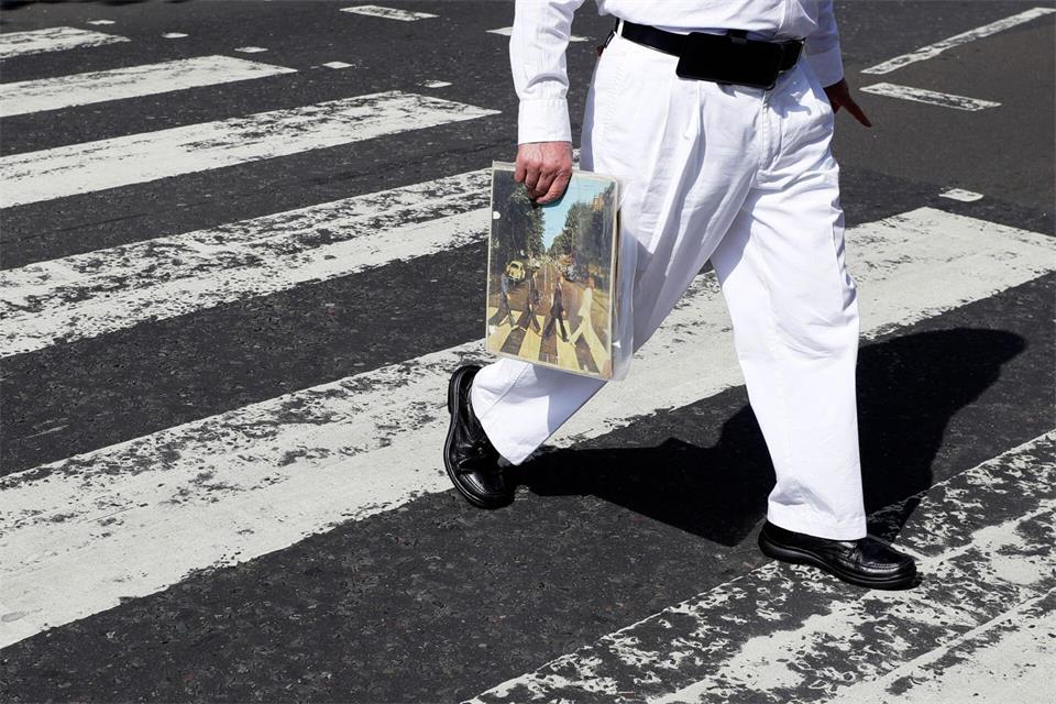Einer der berühmtesten Zebrastreifen der Welt: Ein Fan trägt eine Ausgabe des Beatles-Albums „Abbey Road“, als er die Abbey Road überquert. (Archivfoto)Kirsty Wigglesworth/AP/dpa