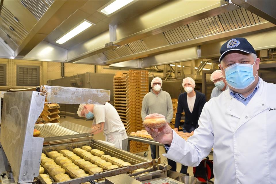 Einer von 4800: Bäckermeister Bastian Bors zeigt einen Berliner, die für den guten Zweck verkauft wurden. Im Hintergrund (von rechts) seine rotarischen Freunde Stefan Sühling, Jan Ridder und Club-Präsident Ingo Bülow.