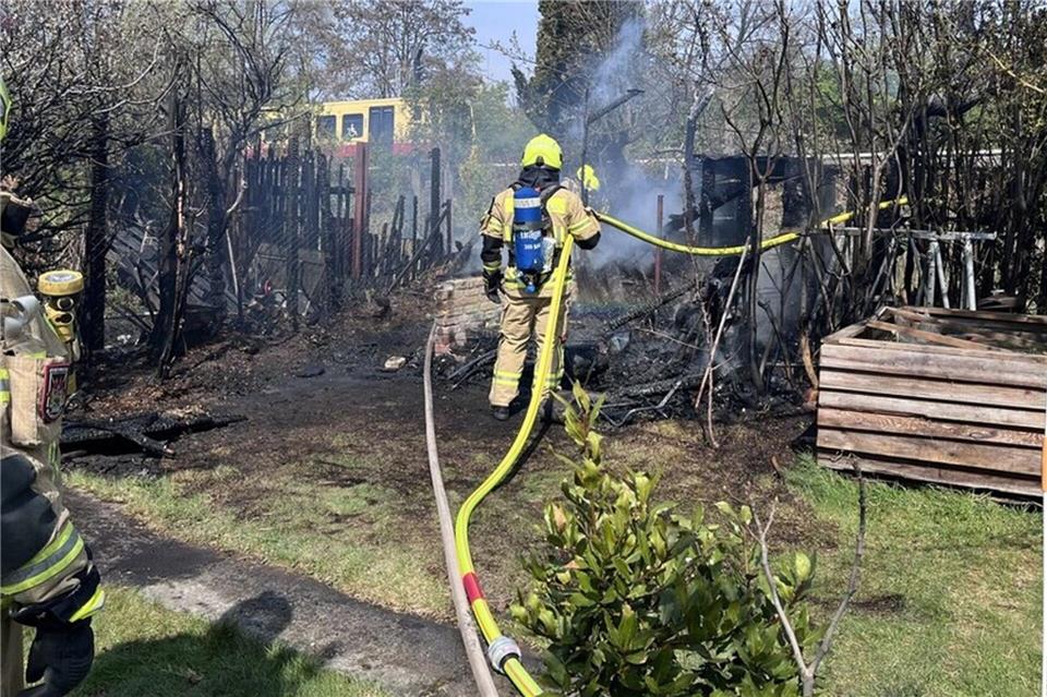 Einsatzkräfte der Feuerwehr löschen den Brand zweier Gartenhäuser. (Handout) ---/Berliner Feuerwehr/dpa