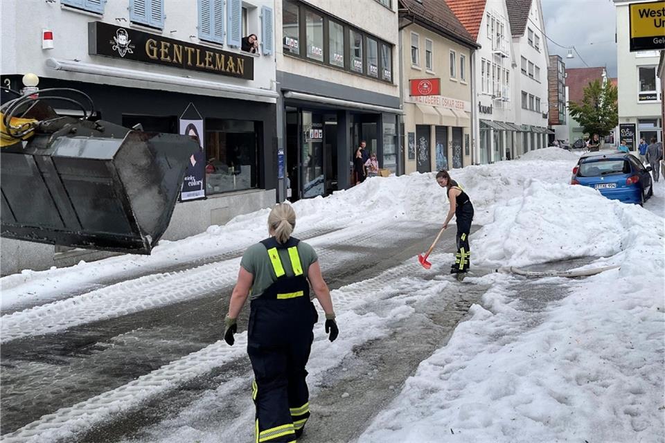 Einsatzkräfte der Feuerwehr räumen Hagel von einer Straße in Reutlingen.