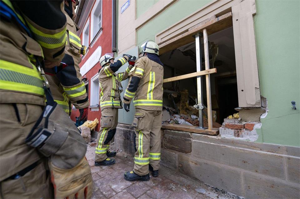 Einsatzkräfte der Feuerwehr sichern die Wand, in der ein großes Loch klafft.Pia Bayer/dpa