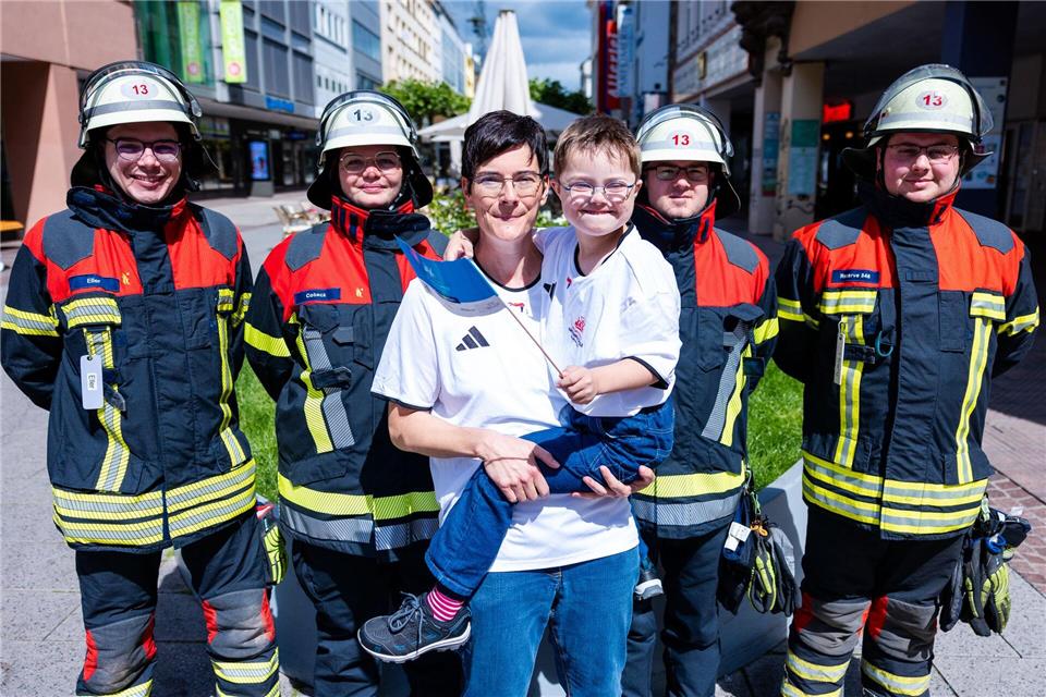 Einsatzkräfte der Freiwilligen Feuerwehr Saarbrücken-St. Johann (LB 13) wünschen dem achtjährigen Elias und seiner Mutter Stephanie Lade vor dem Fackellauf der Special Olympics viel Erfolg.Laszlo Pinter/dpa