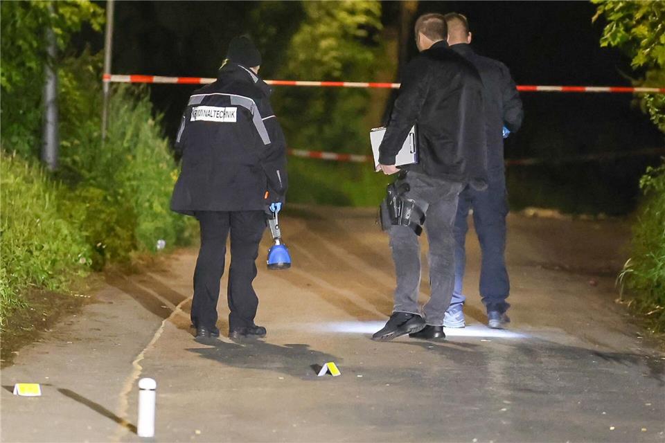 Einsatzkräfte stehen auf einer Straße an einem Tatort und sichern Spuren.Matthi Rosenkranz/dpa