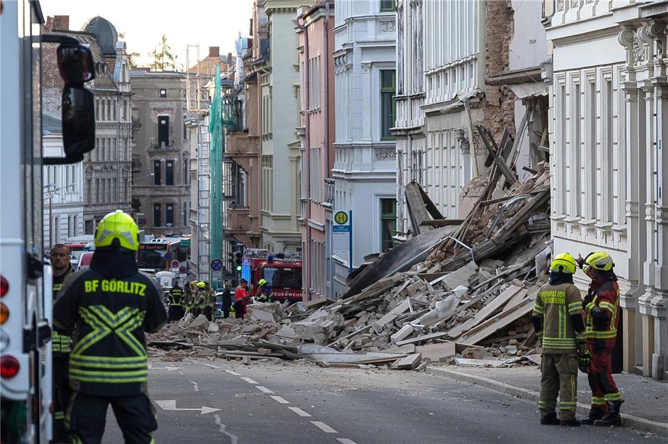 Einsatzkräfte von Polizei und Feuerwehr stehen in der Nähe eines eingestürzten Hauses in Görlitz. Als Ursache vermutet man eine Gasexplosion.Paul Glaser/dpa/dpa-tmn