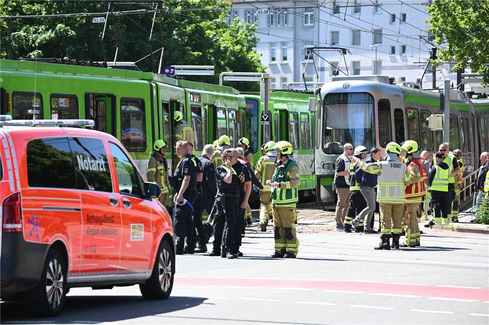 Einsatzkräfte von Polizei und Feuerwehr stehen nach einem Unfall neben zwei Stadtbahnen.Julian Stratenschulte/dpa