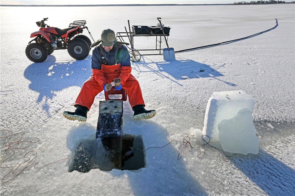 Eisfischer Andy Ahrens klappert auf dem etwa drei Meter langen Brett. Bernd Wüstneck/dpa