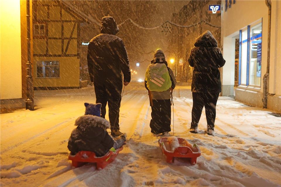 Eltern bringen am frühen Morgen in Wernigerode ihre Kinder mit Schlitten in die Schule. Wintersturm „Elli“ bringt Eiseskälte, Glätte und viel Schnee, so dass Busse und Bahnen teils nur eingeschränkt unterwegs sind.Matthias Bein/dpa