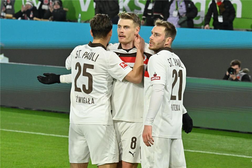 Eric Smith vom FC St. Pauli (m) nach seinem Tor in Wolfsburg.Swen Pförtner/dpa