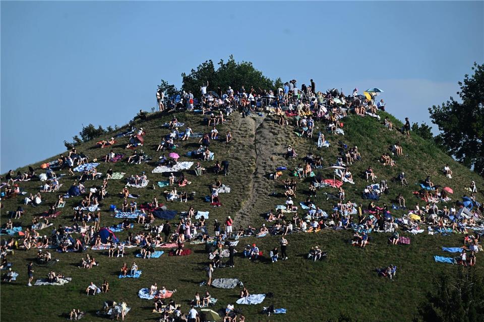Erste Besucher bevölkern den Olympiaberg im Münchner Olympiapark, um von dort die partielle Sonnenfinsternis zu beobachten.Felix Hörhager/dpa