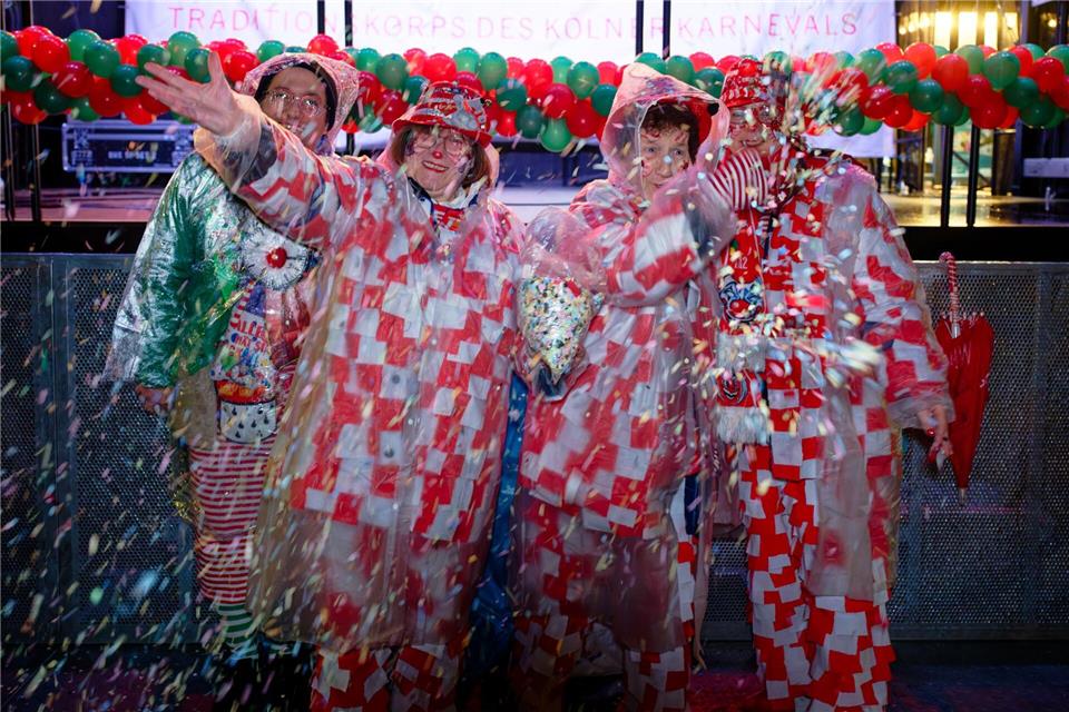Erste Jecken warten im Regen auf dem Alter Markt an Weiberfastnacht auf den Beginn des Straßenkarnevals in Köln.Henning Kaiser/dpa