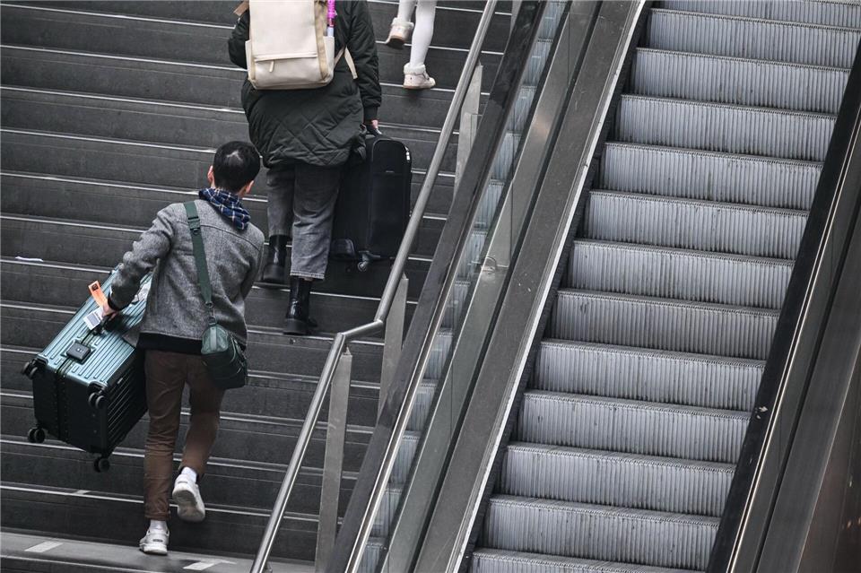 Fahrgäste tragen ihre Koffer am Berliner Hauptbahnhof über die Treppe. (Archivbild)Britta Pedersen/dpa