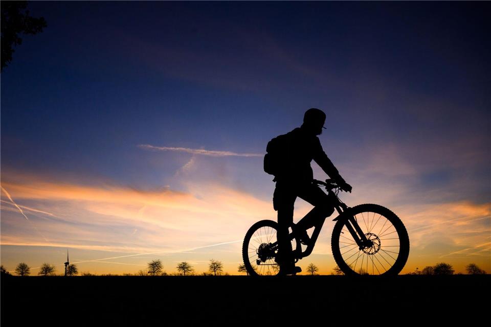 Fahrradfahrer im Morgengrauen: Silhouette vor Sonnenaufgangshimmel in Hannover.Julian Stratenschulte/dpa