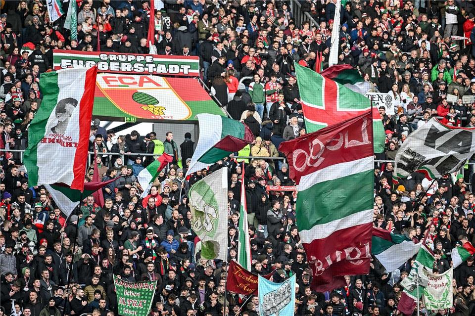 Fans des FC Augsburg schwenken ihre Fahnen in der WWK-Arena. (Archivfoto)Harry Langer/dpa