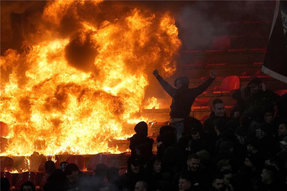 Fans von Partizan Belgrad jubeln vor brennenden Sitzen während des Derbys in der serbischen Fußballliga gegen Roter Stern Belgrad.Darko Vojinovic/AP/dpa