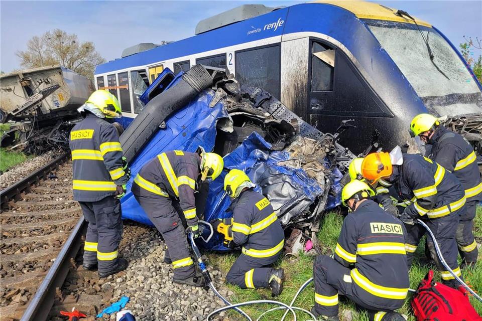 Feuerwehrleute arbeiten am Unglücksort, wo ein Personenzug und ein Lastwagen zusammengestoßen sind. Bei dem Unglück kam eine Person ums Leben, 21 Menschen wurden verletzt.-/Feuerwehr- und Rettungsdienst Trnava/TASR/dpa