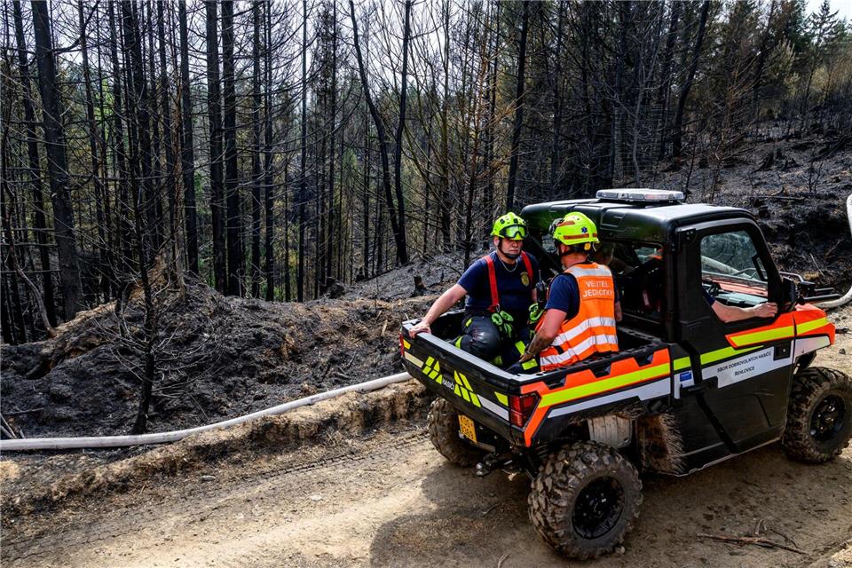 Feuerwehrleute fahren mit einem geländegängigen Einsatzfahrzeug auf einem Waldweg.Hájek Ondøej/CTK/dpa