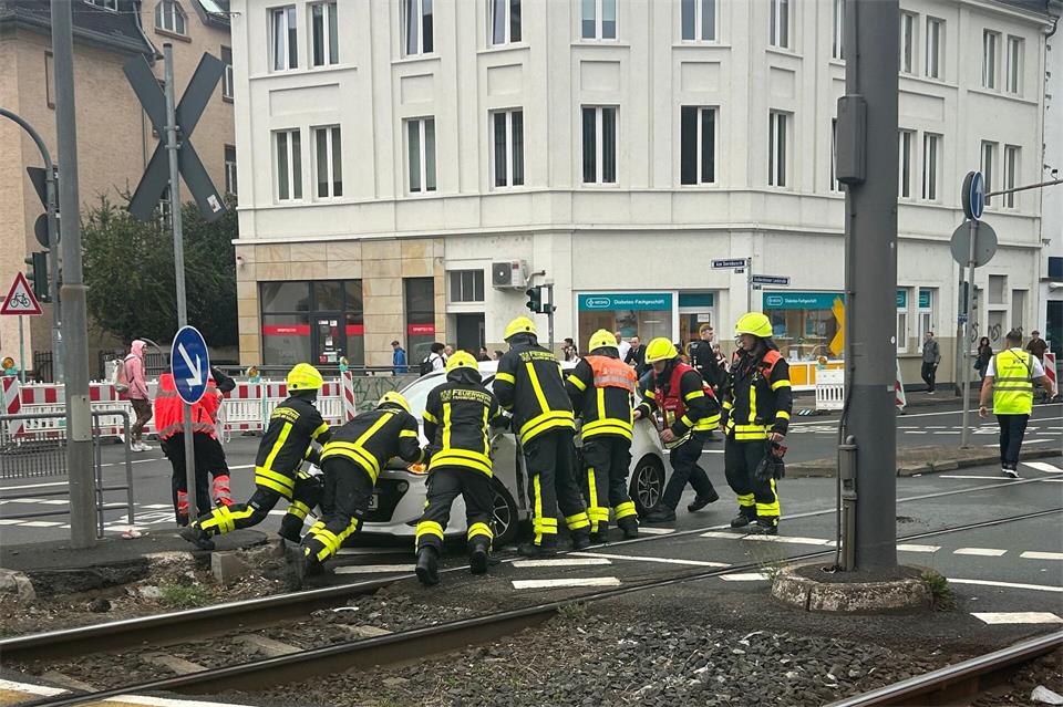 Feuerwehrleute schieben ein beschädigtes Auto von den U-Bahn-Gleisen. Mona Wenisch/dpa