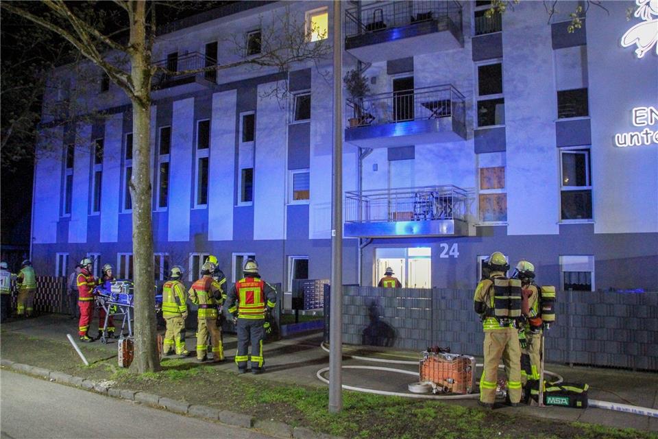 Feuerwehrleute und Rettungskräfte stehen vor einem Haus für betreutes Wohnen, in dem ein Brand ausgebrochen war.