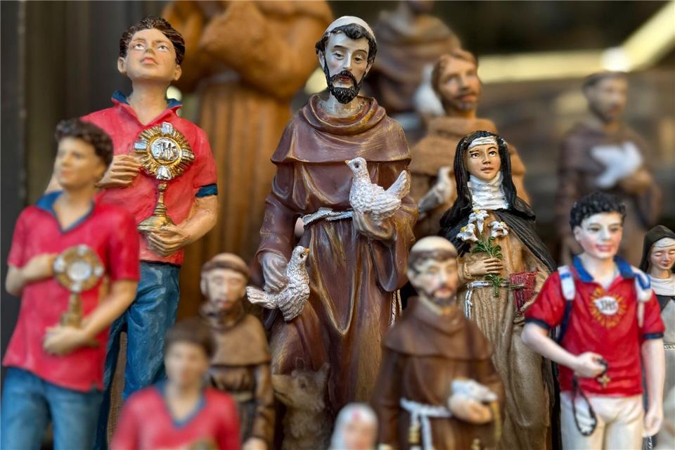 Figuren des alten und des neuen Heiligen stehen in Souvenirshops nebeneinander. (Archivbild)Christoph Sator/dpa