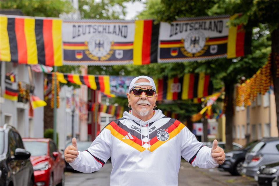 „Flaggen-Achim“ steht in einem Meer aus Fahnen in der Rullichstraße in Essen-Altendorf. Rolf Vennenbernd/dpa