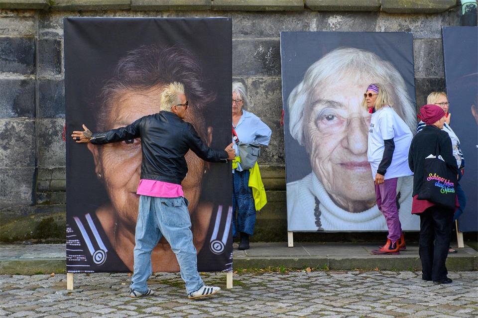 Fotograf Luigi Toscano trägt ein Porträt eines Holocaust-Überlebenden vor dem Dom.Klaus-Dietmar Gabbert/dpa