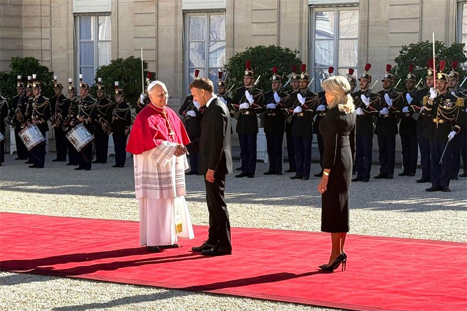 Frankreichs Präsident Emmanuel Macron und seine Ehefrau Brigitte schütteln Hände mit dem Papst im Hof des Élysée-Palastes.Christoph Sator/dpa