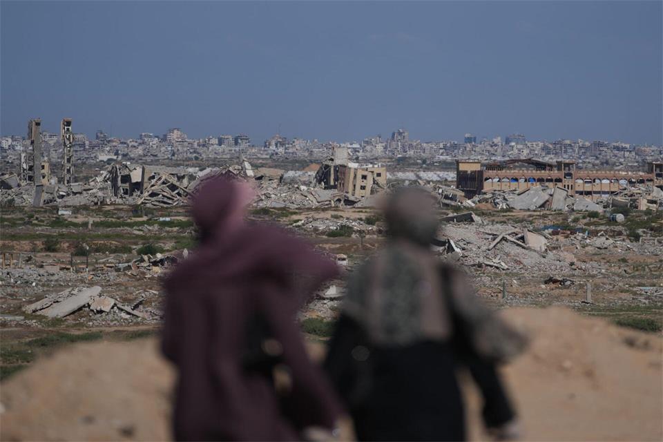 Frauen blicken auf ein stark zerstörtes Gebiet im Zuge des Gaza-Kriegs.Abdel Kareem Hana/AP/dpa