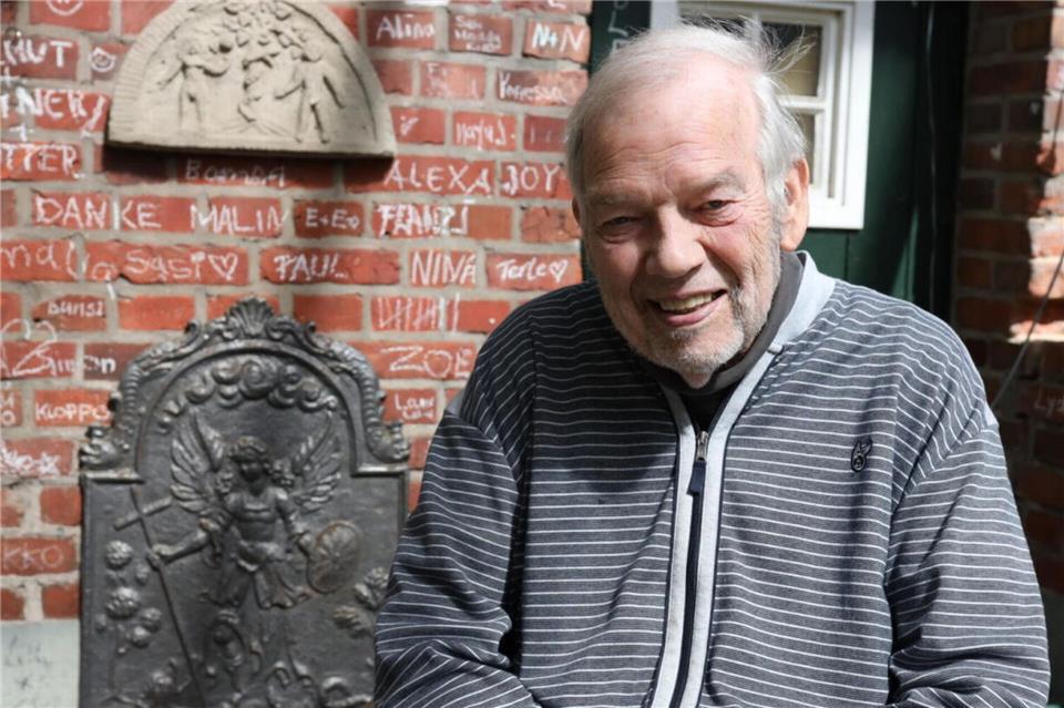 Friedrich Wilhelm Rump sitzt auf der Terrasse des „Sommerhauses“ in Bocholt-Barlo. Im Hintergrund sind Teile der mit Kreide beschriebenen Fassade zu sehen.