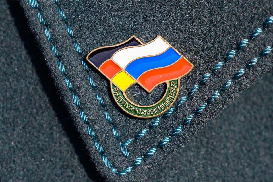 „Für Deutsch-Russische Freundschaft“.: Bei Gedenken zum 81. Jahrestag der Schlacht auf den Seelower Höhen trägt ein Teilnehmer einen Ansteckpin mit den Flaggen von Deutschland und Russland. Patrick Pleul/dpa