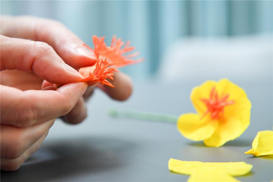 Für die Blütenfüllung den eingeschnittenen Krepppapier-Streifen um den Blumendraht wickeln und alles mit Floristen-Band fixieren.Zacharie Scheurer/dpa-tmn