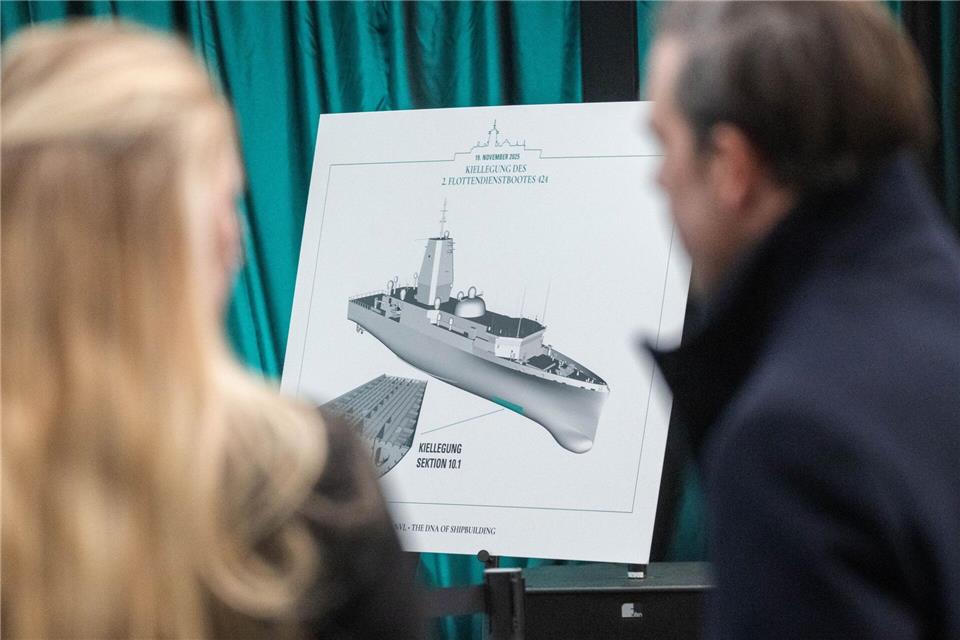 Gäste betrachten in der Werfthalle der Peene-Werft eine Zeichnung des neuen Flottendienstbootes. Stefan Sauer/dpa