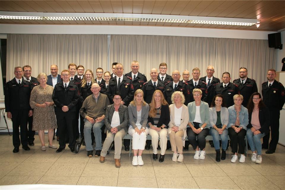 Geehrte und Beförderte mit Familienmitgliedern: der stellvertretende Wehrleiter Kai Sobbe (von links), Löschzugführer André Klinkenberg, Ortsvorsteherin Maria Schulde und der Erste Beigeordneter Norbert Nießing. Clemens Wansing (sitzend) wurde besonders geehrt.
