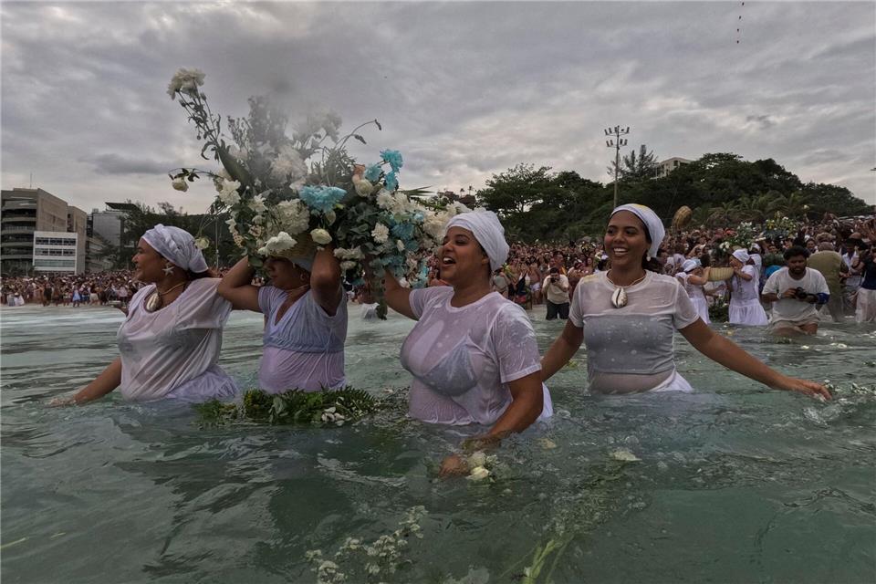 Gläubige werfen Blumen in das Wasser.Bruna Prado/AP/dpa
