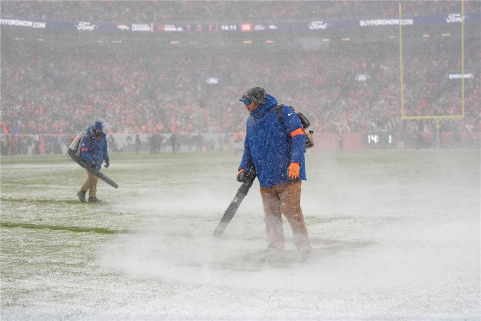 Greenkeeper der Denver Broncos blasen den Schnee von den Yard-Linien.Ashley Landis/AP/dpa