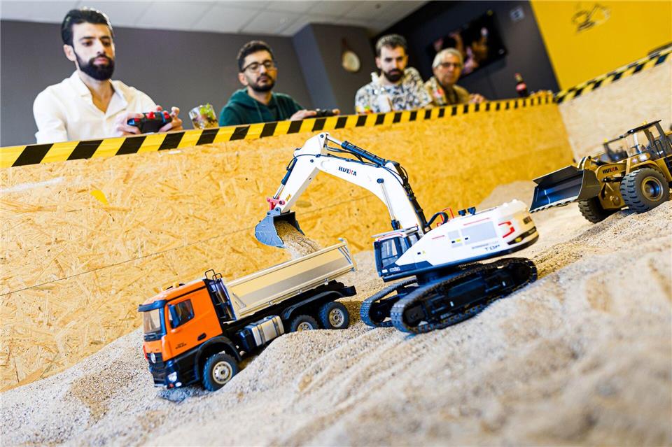 Gründer Siymo Othman (links) steuert mit Freunden kleine Bagger, Radlader und Lastwagen in seinem neu eröffneten Bagger-Café. Es soll das erste dieser Art in Deutschland sein.Moritz Frankenberg/dpa