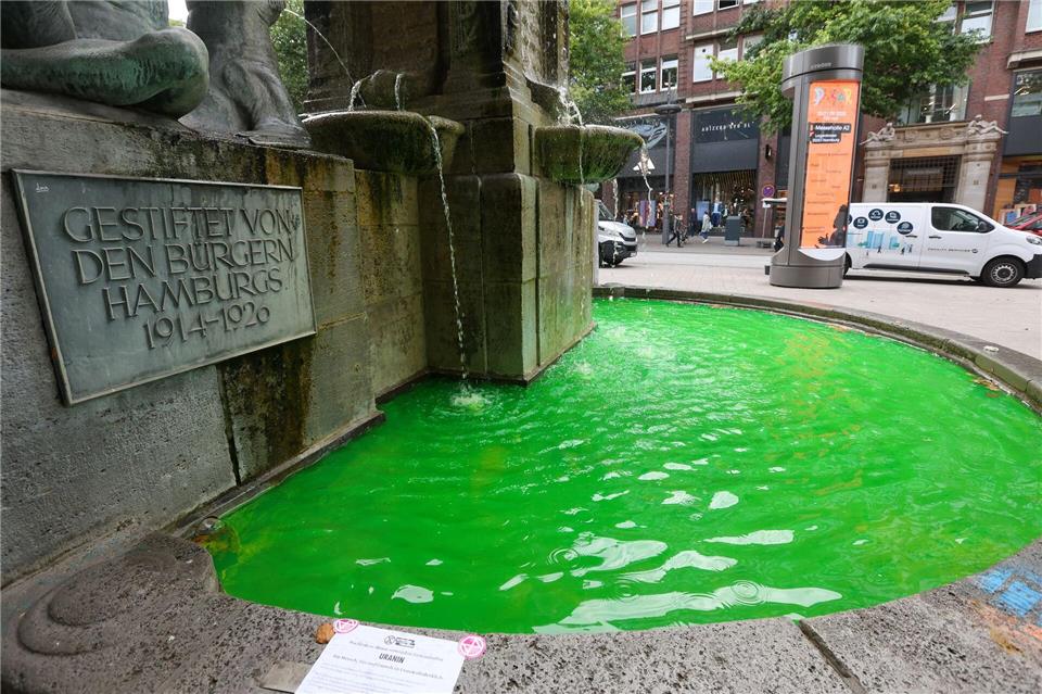 Grünes Brunnenwasser in Hamburg - Klimaaktivisten haben mehrere Brunnen in der Hansestadt mit Uranin eingefärbt, um gegen Kreuzfahrt und LNG-Technologie zu protestieren. Bodo Marks/dpa