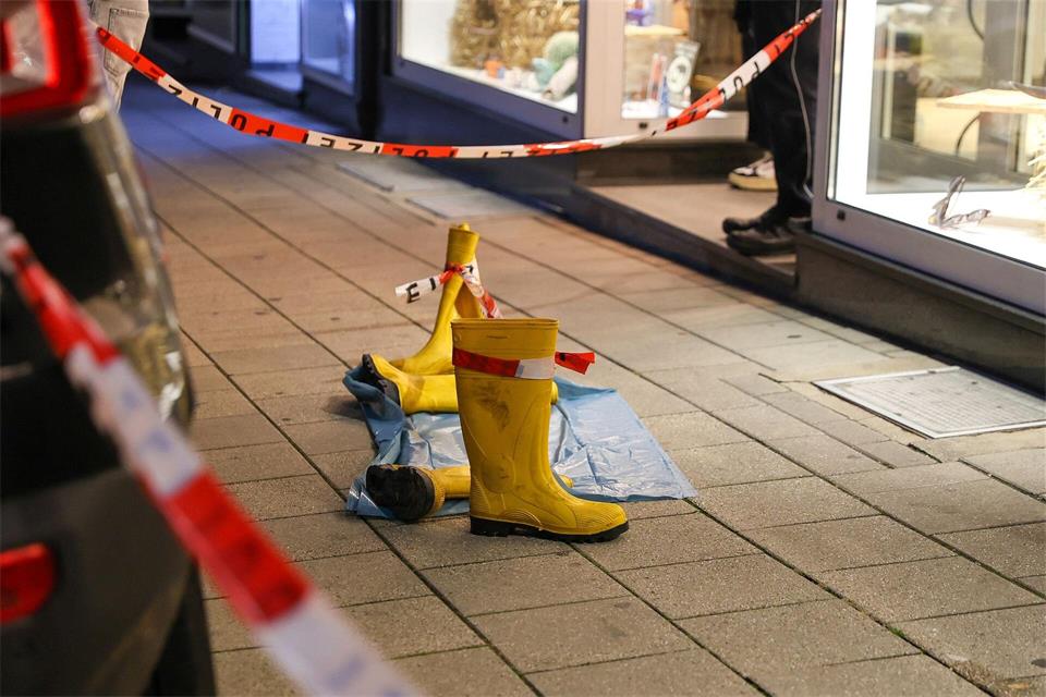 Gummistiefel wurden auf eine blaue Plane gestellt und mit Absperrband verbunden.Matthias Rosenkranz/dpa