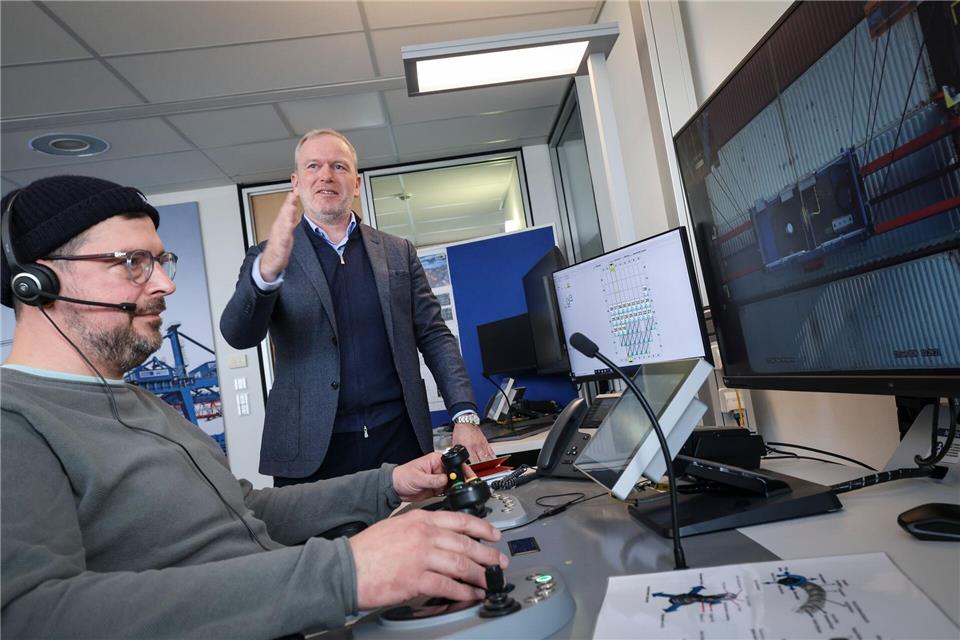 HHLA-Firmenchef Eijsink gestikuliert neben einem Mitarbeiter, der eine Containerbrücke steuert. Christian Charisius/dpa