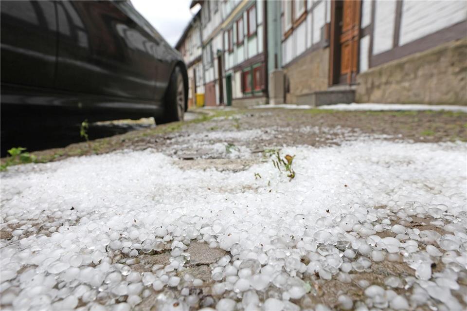 Hagelkörner bedecken nach einem Gewitter einen Gehweg in Derenburg.Matthias Bein/dpa