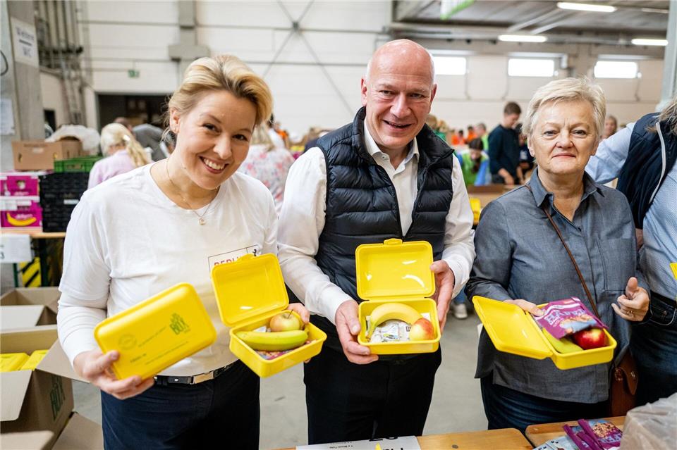 Am Montag gibts Geschenke für Erstklässler Halfen beim Packen der Bio-Brotdosen mit: Wirtschaftssenatorin Franziska Giffey (SPD, l), der Regierende Bürgermeister Kai Wegner (CDU) und Mit-Initiatorin Renate Künast (Bündnis 90/Die Grünen).Fabian Sommer/dpa