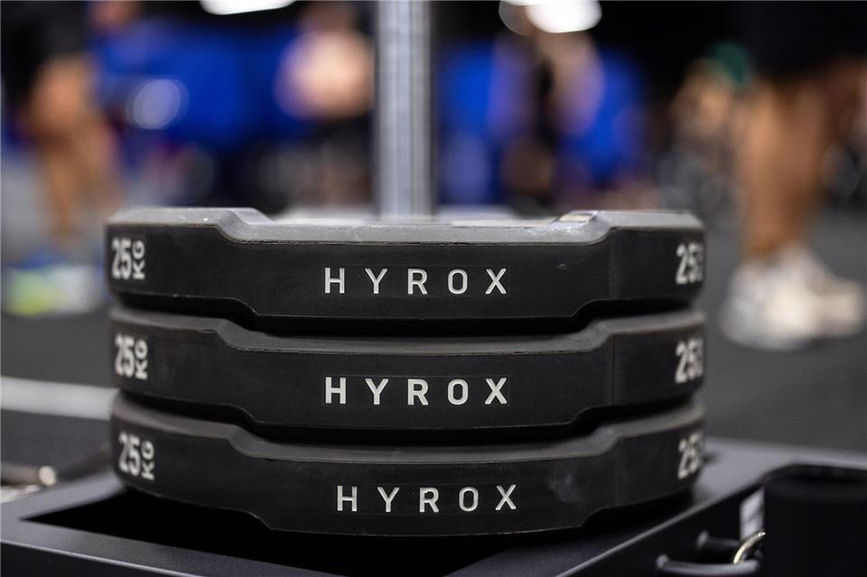 Hantelscheiben mit dem Schriftzug Hyrox an einem Messestand, wo wenig später ein Lauf- und Workout-Wettbewerb stattfinden sollte.Rolf Vennenbernd/dpa